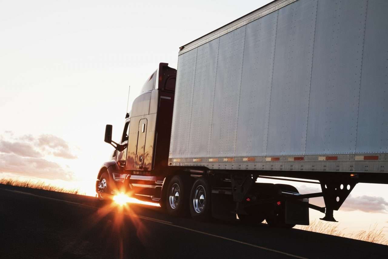 silhouette-of-a-commercial-truck-driving-on-a-highway-at-sunset-.jpg